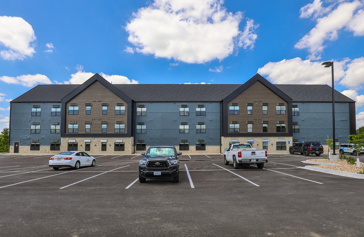 Front elevation across the parking lot with parked cars, three gables